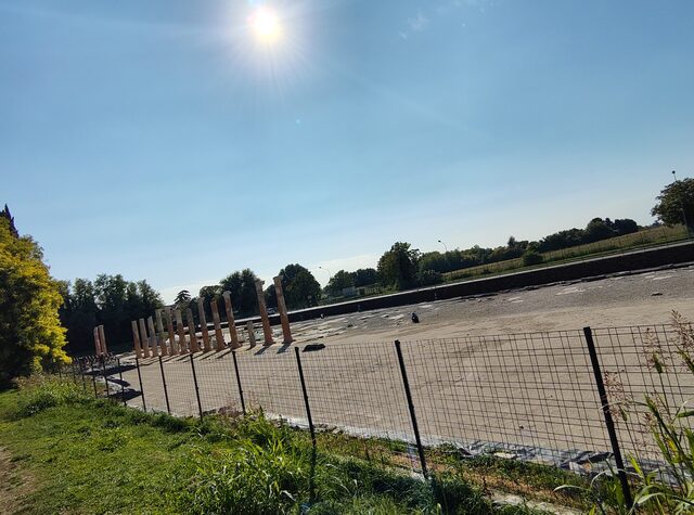 Eingezäunte Ausgrabungsstätte in Aquileia mit einer Reihe römischer Säulen im Gegenlicht