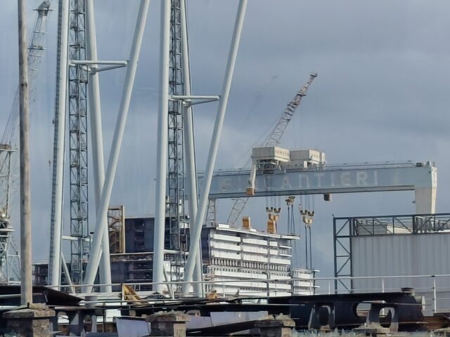 Kräne der Fincantieri-Werft in Monfalcone, darunter ein Kreuzfahrtschiff im Bau, aus großen Modulen zusammengesetzt